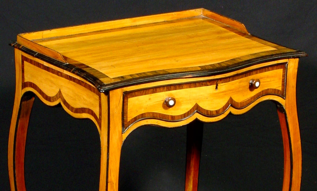 The shaped top over a conforming frieze drawer; raised on ebony banded attenuated cabriole legs with rosewood and calamander banding throughout.