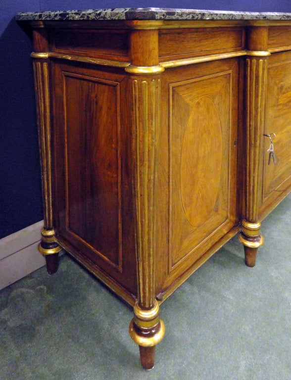 In the manner of Henry Holland,The later verde antico marble top over panelled frieze above three cupboard doors each opening to two shelves; flanked by engaged fluted columns over a gilt-banded apron on turned tapering feet.