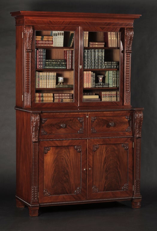 The projecting cornice above a pair of bead-molded glazed doors flanked by boldly carved corbels & stiles, over a lower part incorporating a fully fitted secretaire drawer, paneled doors opening to sliding trays concealing secret drawers set to each