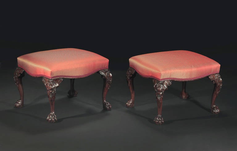 The upholstered seats with a shaped apron and raised on cabriole legs with boldly carved knees incorporating acanthus leaves and floral sprays, terminating in claw feet.