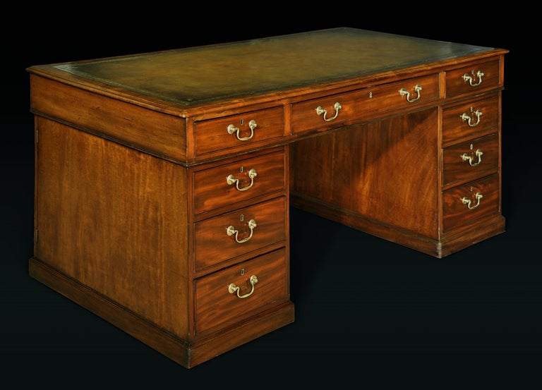 The rectangular leather-inset top over a frieze fitted with three short drawers; raised on pedestals each fitted with drawers to one side and a cabinet enclosing a fixed shelf to the other; on a plinth base.