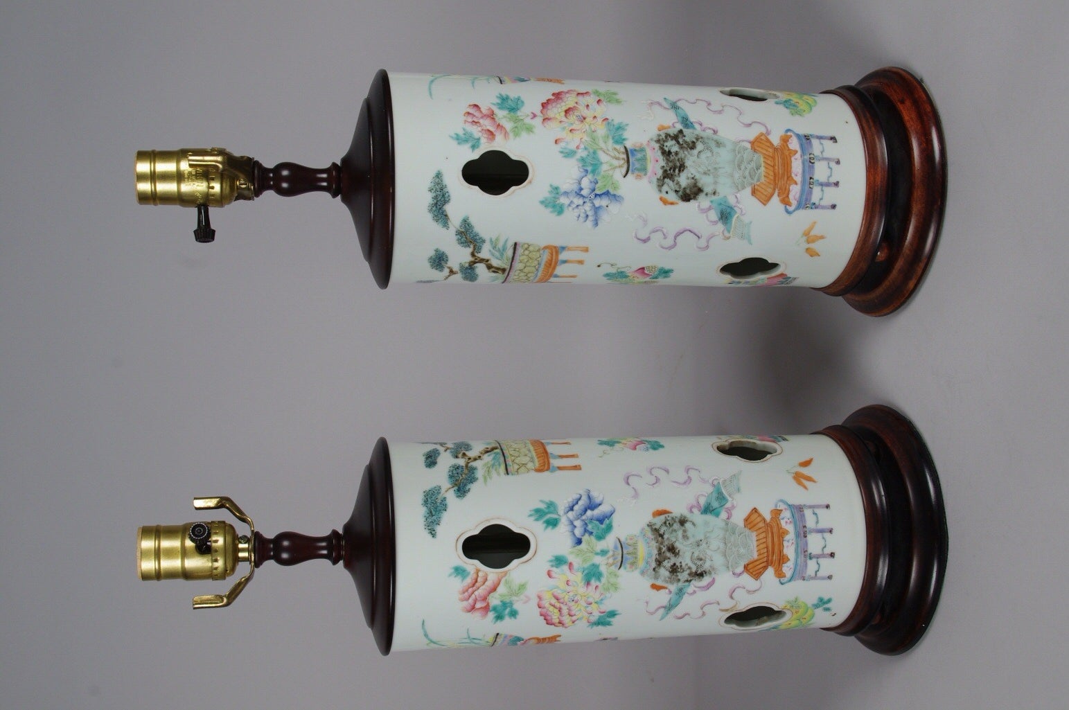 Pair of Chinese porcelain famille rose hat stands, each pierced with ventilation holes and well painted with a large vase of peonies and chrysanthemums on a stand; festooned with brightly painted symbols and motifs.

This is a true pair, as seen