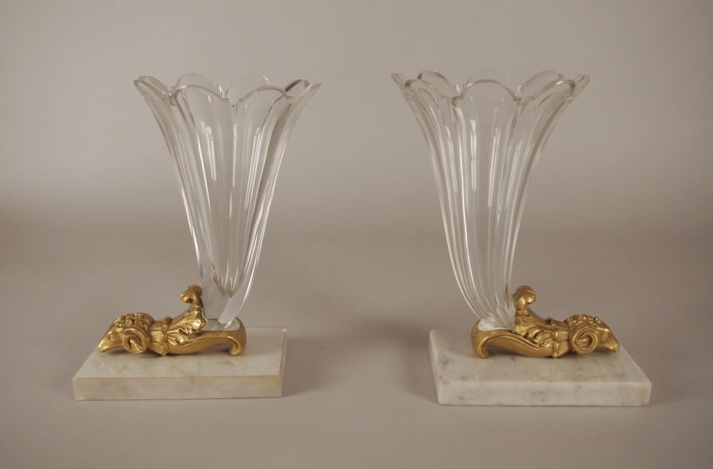 Pair of Crystal and Bronze Ram's Head Coprnucopias, each with a finely blown and cut cornucopia mounted to a well cast ans chased bronze ram's head, on a white marble base.