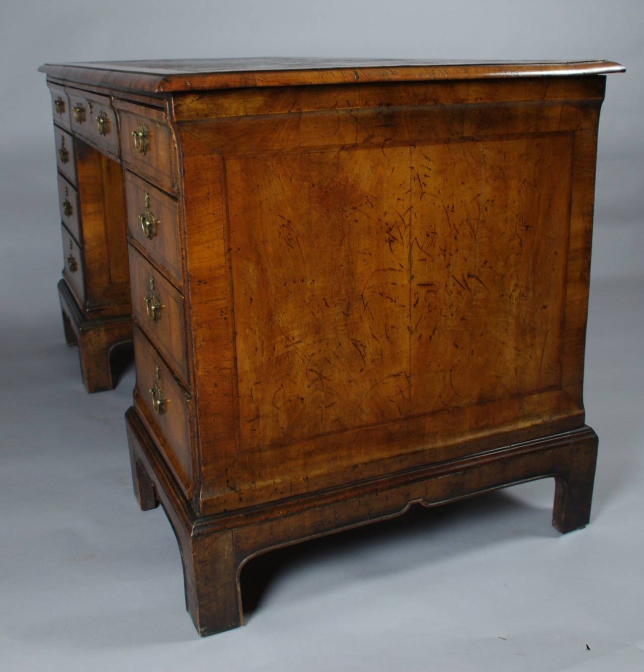 George III walnut pedestal desk, the rectangular top with beautiful early tooled leather set within a crossbanded border and molded edge; the well figured drawers with herringbone stringing and replaced hardware raised on bracket feet with a beaded