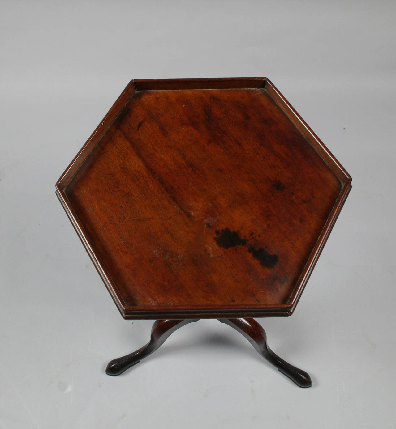 George III mahogany tripod wine table, the hexagonal galleried top with delicate string inlay to the edge; the well-turned center post raised on three cabriole legs with slipper feet.

This elegant little table differs from the more conventional