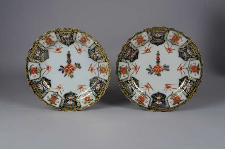 Pair of Meissen Imari plates, each painted in overglaze orange and underglaze blue, the decoration centered with a large spray surrounded by six flower sprigs, the lambrequin border of alternating panels of chrysanthemum and stylized louts, the