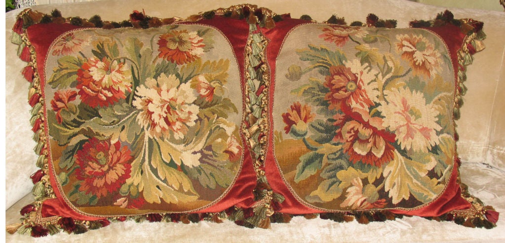 Stunning pair of vibrant woven aubusson fragments of generous scale depicting bountiful floral bouquets framed within decorative ribbon tape on red silk mohair with multi-colored tassel trim and backed with gold diamond stitched silk dupioni