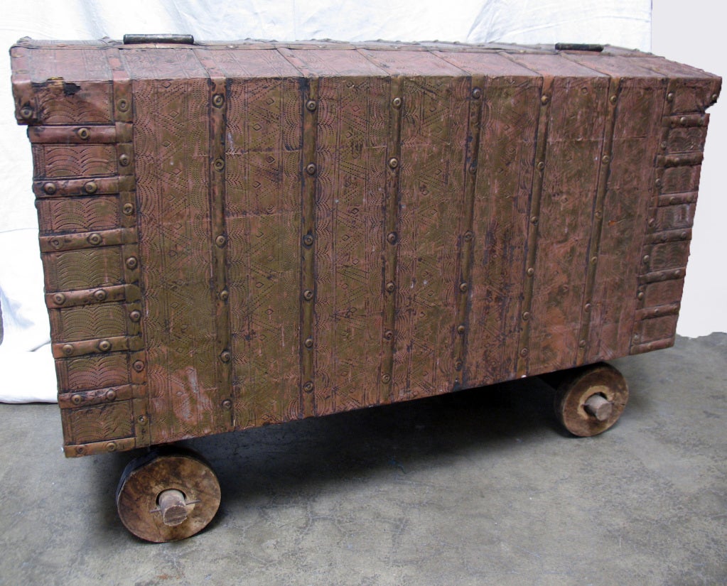 Handsome metal trunk/dowry chest with wheels,brass strapping, hand stamped geometric design amidst birds, lions, floral decoration,hand forged hardware and side handles with slightly domed top.  Great Scale for a coffee table.