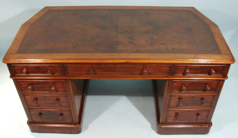 An unusual Georgian style mahogany kneehole desk, probably a custom piece for an alcove, the shaped leather lined top of angular form with 3 frieze drawers resting on conforming shaped pedestals each with 3 graduated drawers all resting on a plinth