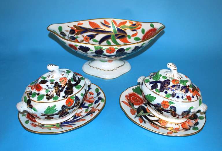A grouping of 2 Worcester covered sauce tureens and underplates together with a matching centerpiece, with stylized foliate decoration including peonies chrysantheum and poppies in blue, green, gold and ochre.