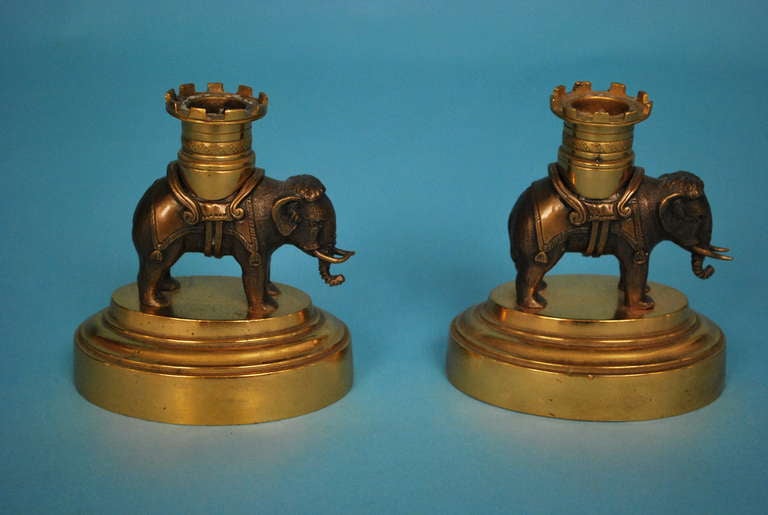 A charming and well- executed pair of French bronze and gilt metal candlesticks depicting Indian Elephants with removable castle form bobeche, circa 1850-1880.