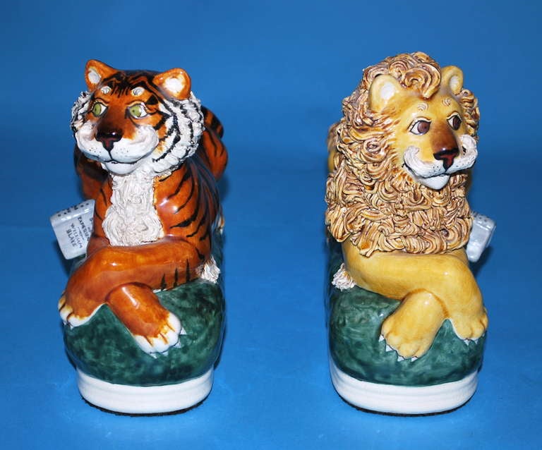 A charming and well-modelled pair of Staffordshire style ceramic figures depicting a smiling lion and tiger, the former with a copy of Blake's 