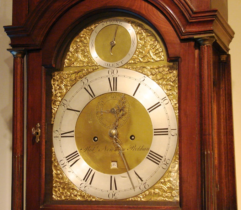 A late Georgian mahogany 8-day time and strike tall case clock, the rectangular hood with arched molded cornice inset lattice panel, raised on gilt mounted columns enclosing an arched door.  Made and signed by  Robert Newman Peckham, circa 1800.