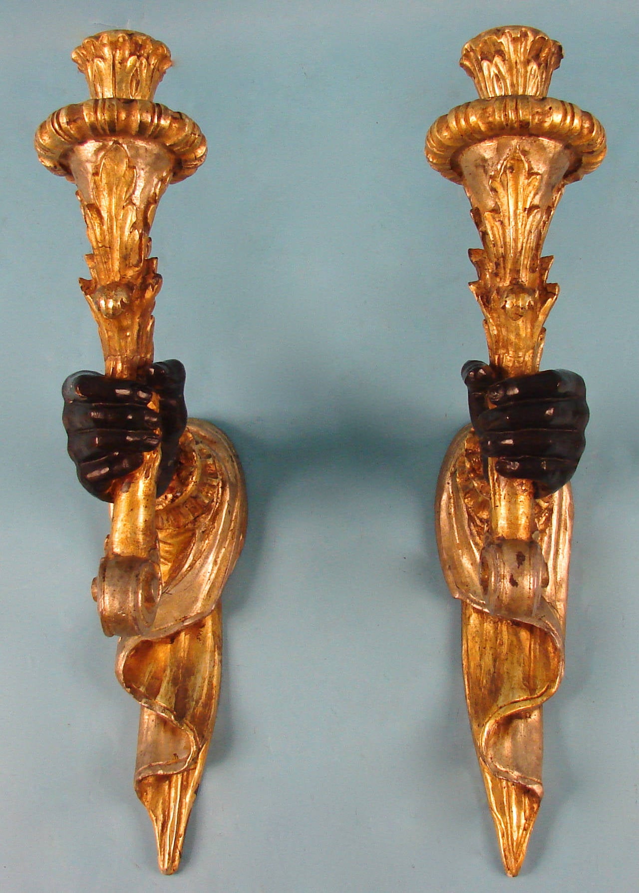 A pretty pair of Venetian giltwood and painted bras de lumiere in the form of a hand holding a torch with a folded drapery backdrop, circa 1880.