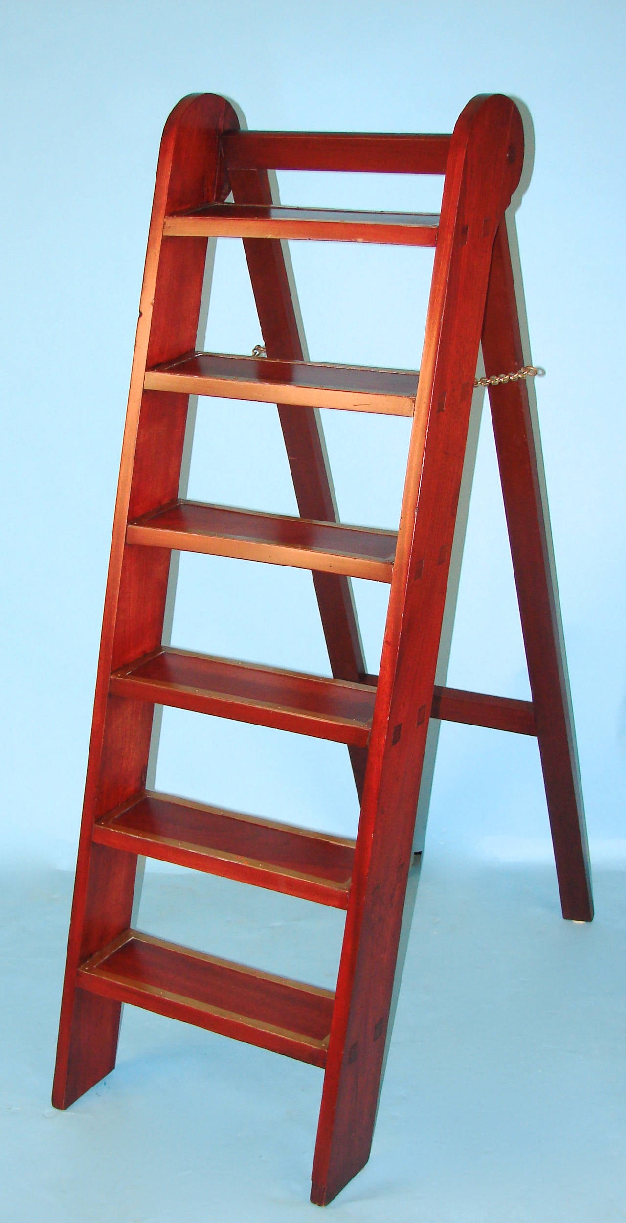 An English mahogany or padouk folding library ladder with six brass bound steps, each mortised through to the sides, circa 1880.