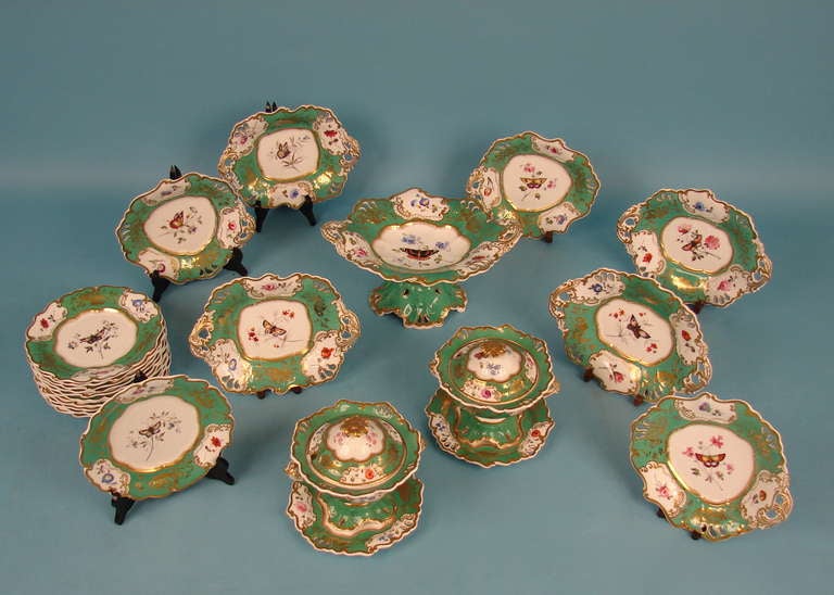 A lovely Rockingham dessert service, each scalloped edge piece decorated with an apple green border with central floral and butterfly reserve all with  gold rims. The set consists of 12 luncheon plates, 7 serving platters, 2 covered tureens with