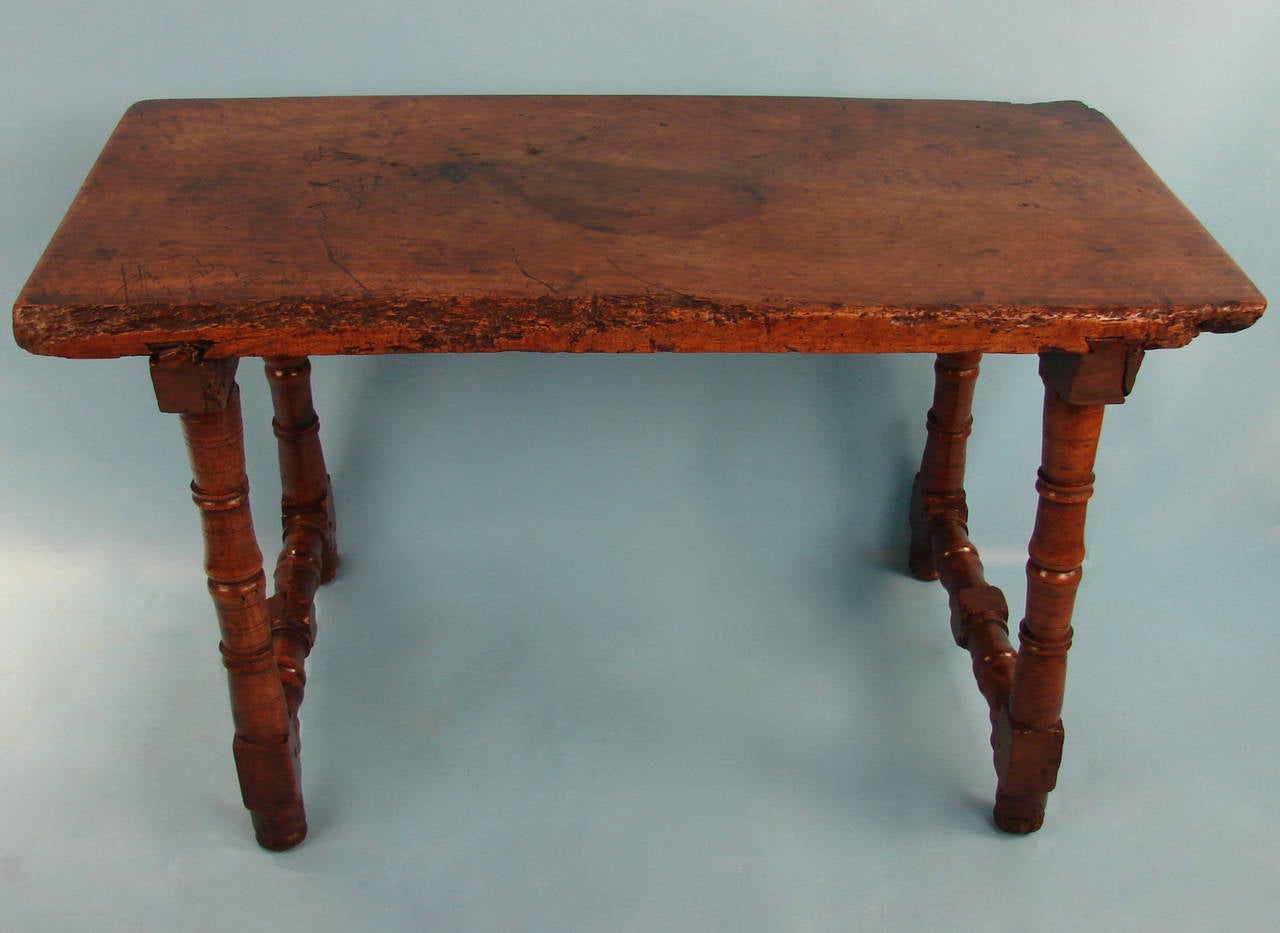 A Spanish Baroque walnut table of simple form, the plank top supported by turned legs joined by stretchers. Bearing old shipping label under top, circa 1700-1740.