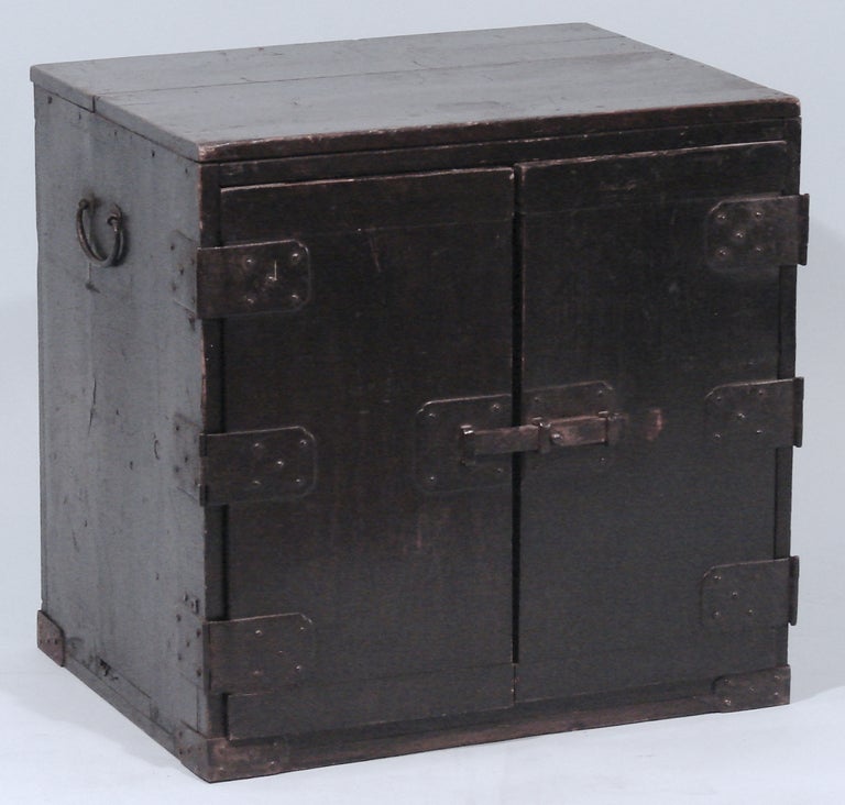 A Japanese Meiji period paint decorated wooden cabinet, the iron mounted doors opening to reveal four graduated drawers marked with Japanese characters.