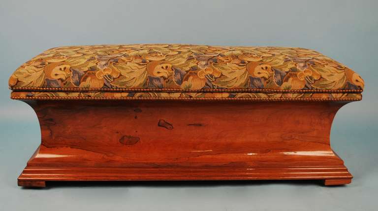 An  English rosewood ottoman, the tapestry upholstered rectangular top opening to a later lined compartment over a concave base raised on a stepped plinth and block feet.  Circa 1850.