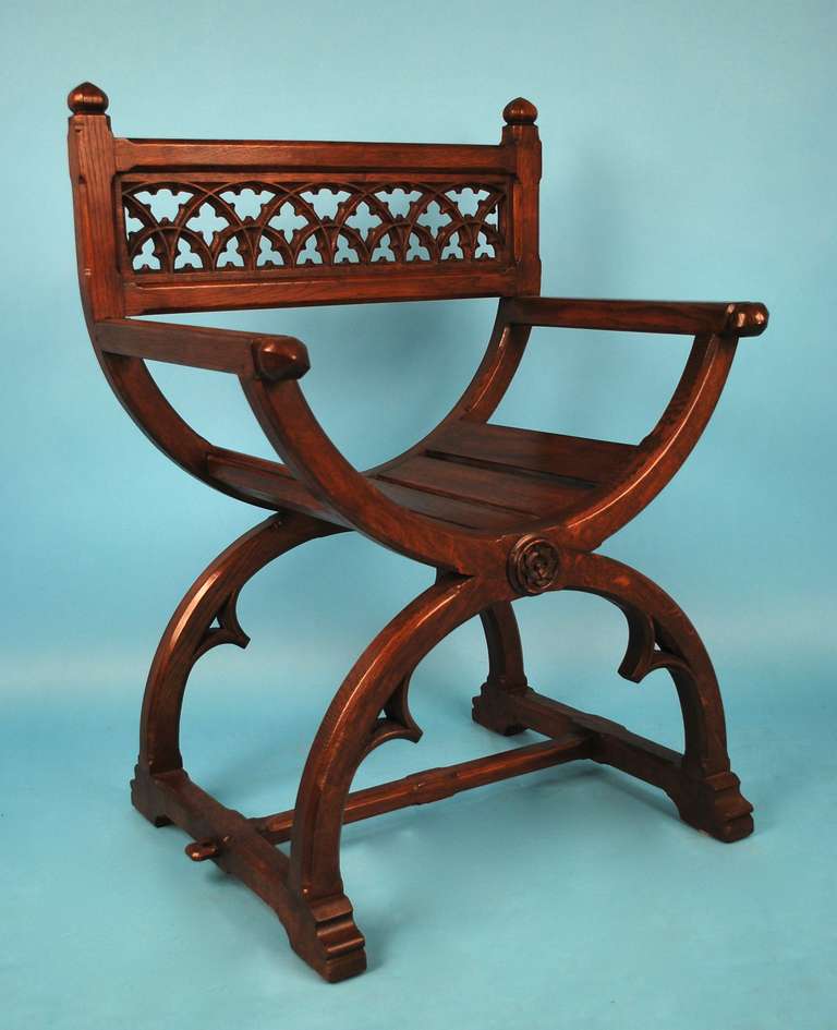 An English Gothic Revival oak Glastonbury armchair, the back pierced with tracery decoration over curule supports, circa 1830.