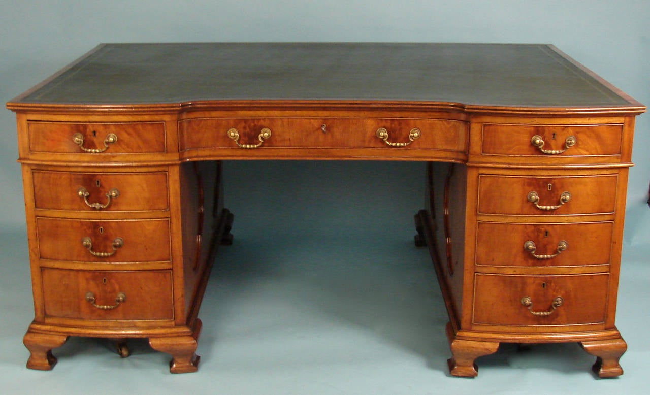 A fine quality English mahogany partners desk, the green tooled leather top above three frieze drawers and six graduated bow front drawers on one side with three frieze drawers and cupboards on the reverse, the sides with shaped inset lozenges, all