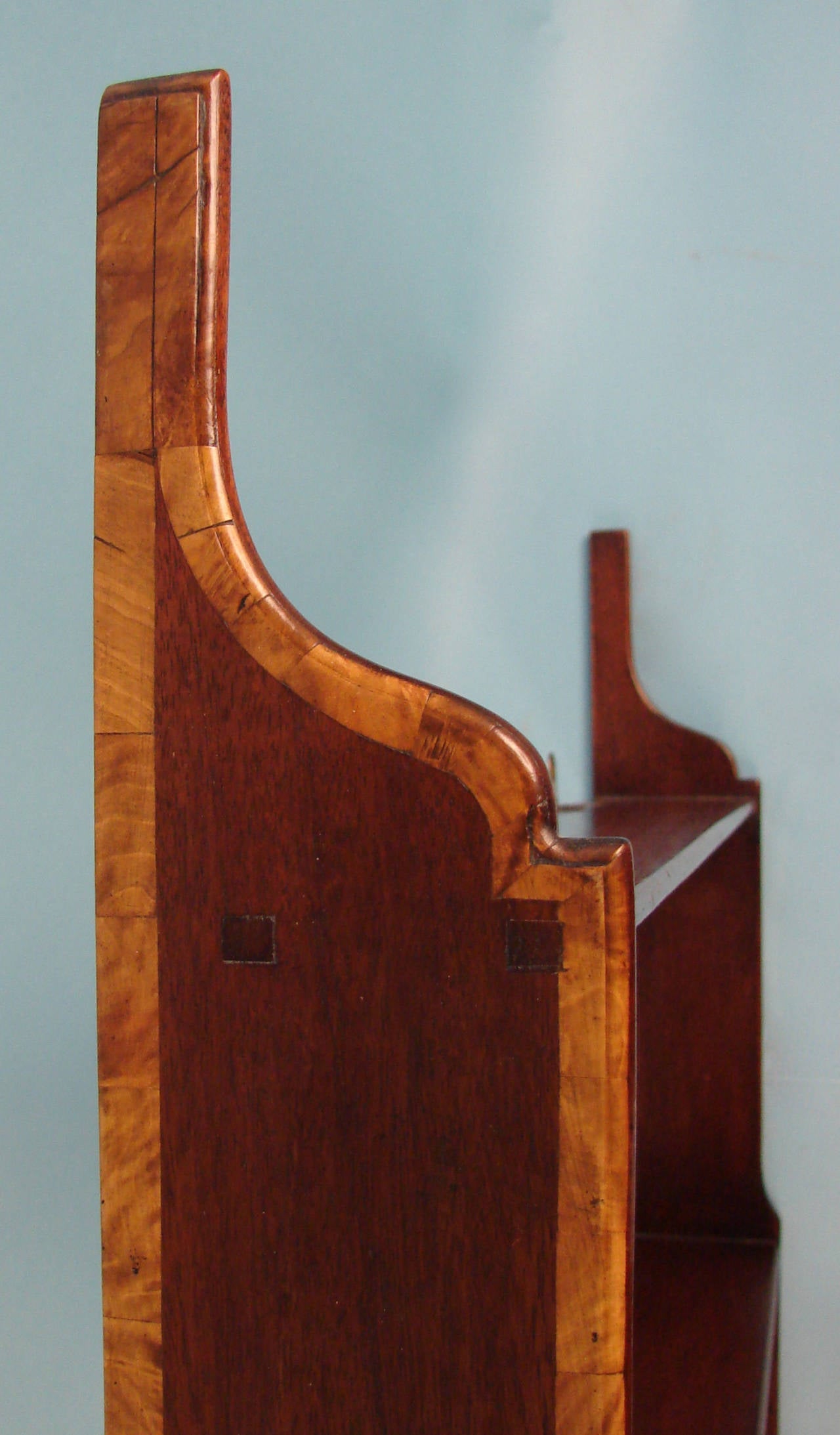 An elegant English mahogany open hanging shelf, the satinwood inlaid shaped sides supporting 3 long and 2 short shelves. Circa 1800.