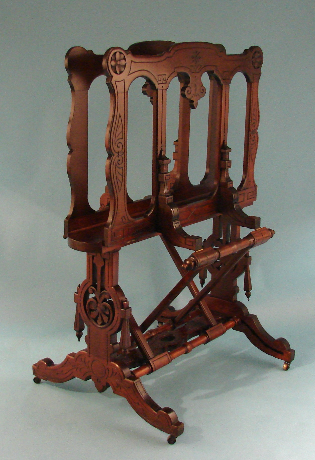 An American Victorian period walnut folio or print stand, the adjustable top section mounted on a conforming base all in the Eastlake taste with incised decoration and attractive carving throughout. Rests on splayed legs ending in casters.
