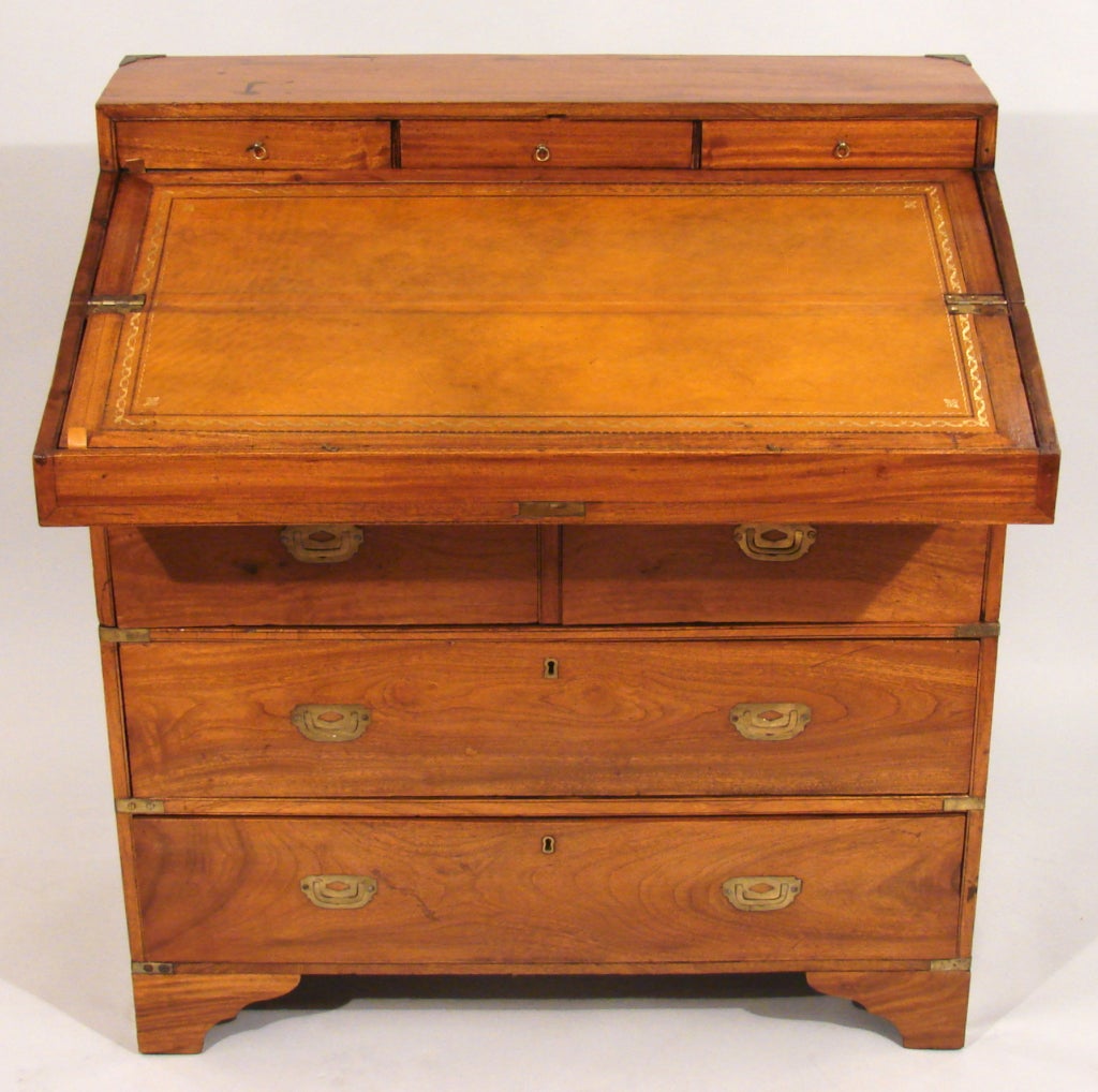 A Chinese export  brass mounted camphor wood campaign desk in 2 parts, the upper case with hinged top opening to a tooled leather writing surface beneath an arrangement of drawers and wells above the lower case consisting of 2 short and 2 long