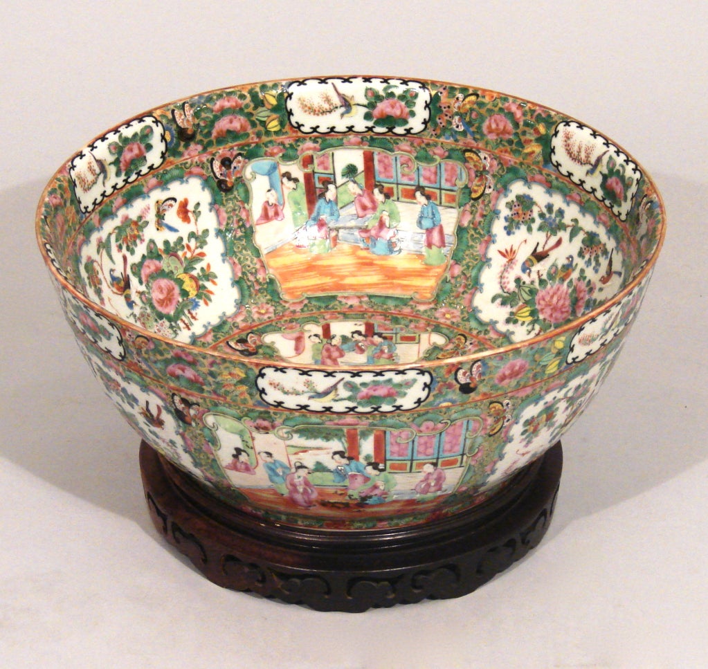 A large Chinese Famille Rose punch bowl of decorated overall with figures, flowers, birds and butterflies now on a later carved wooden stand.