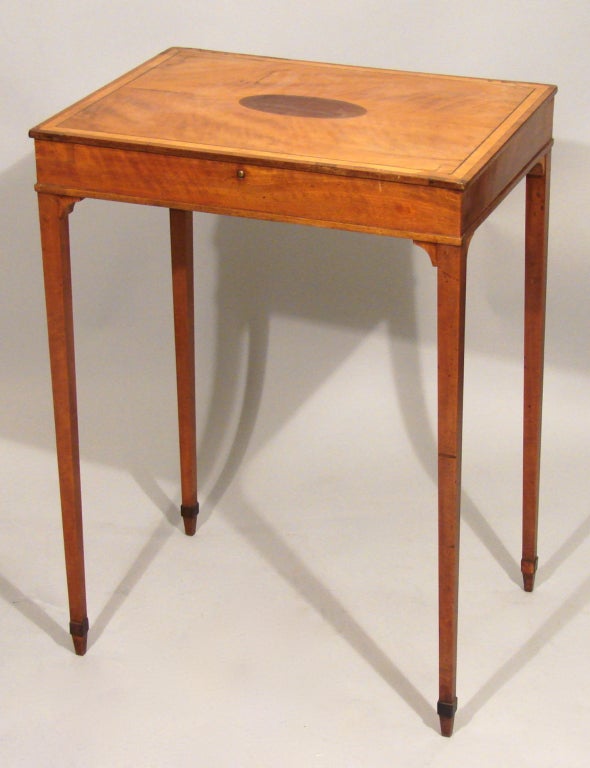A Hepplewhite period satinwood work table. The hinged crossbanded top opening to reveal a well, all on squared tapered legs.
