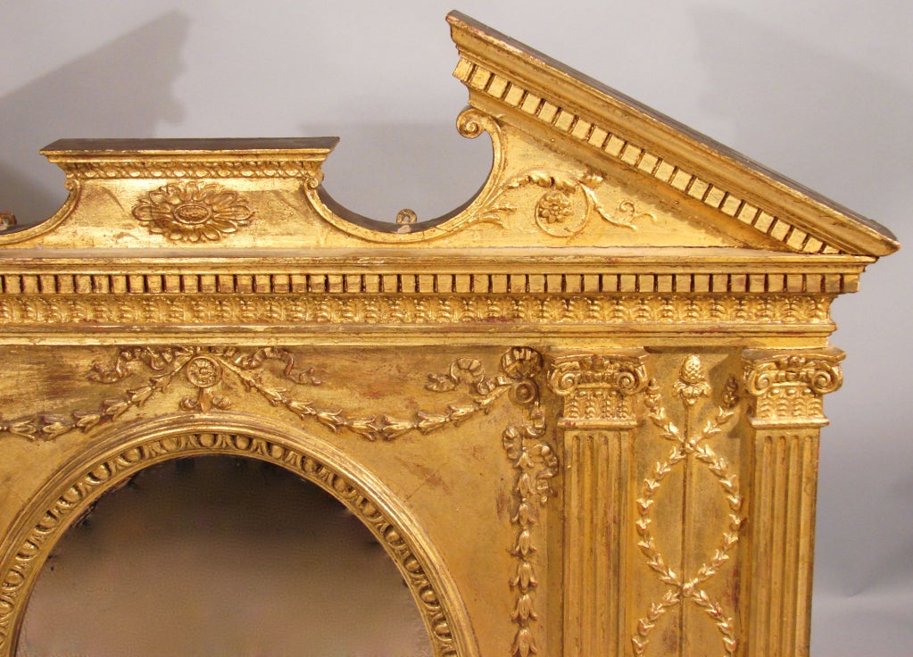 An English Adam style gilt and painted over-mantle mirror the broken pediment top with dentil mouldings over 4 floral decorated columnar sides on a narrow plinth base.