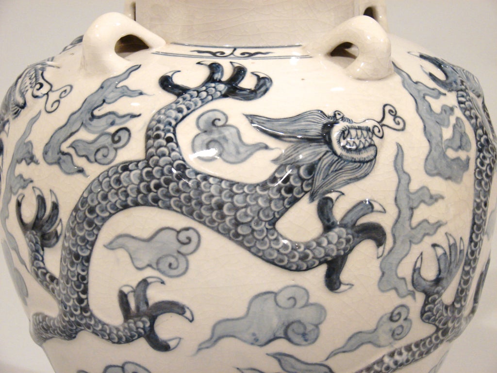 A large Chinese blue and white porcelain table lamp, with four loop handles below the neck, decorated with relief figures of dragons.