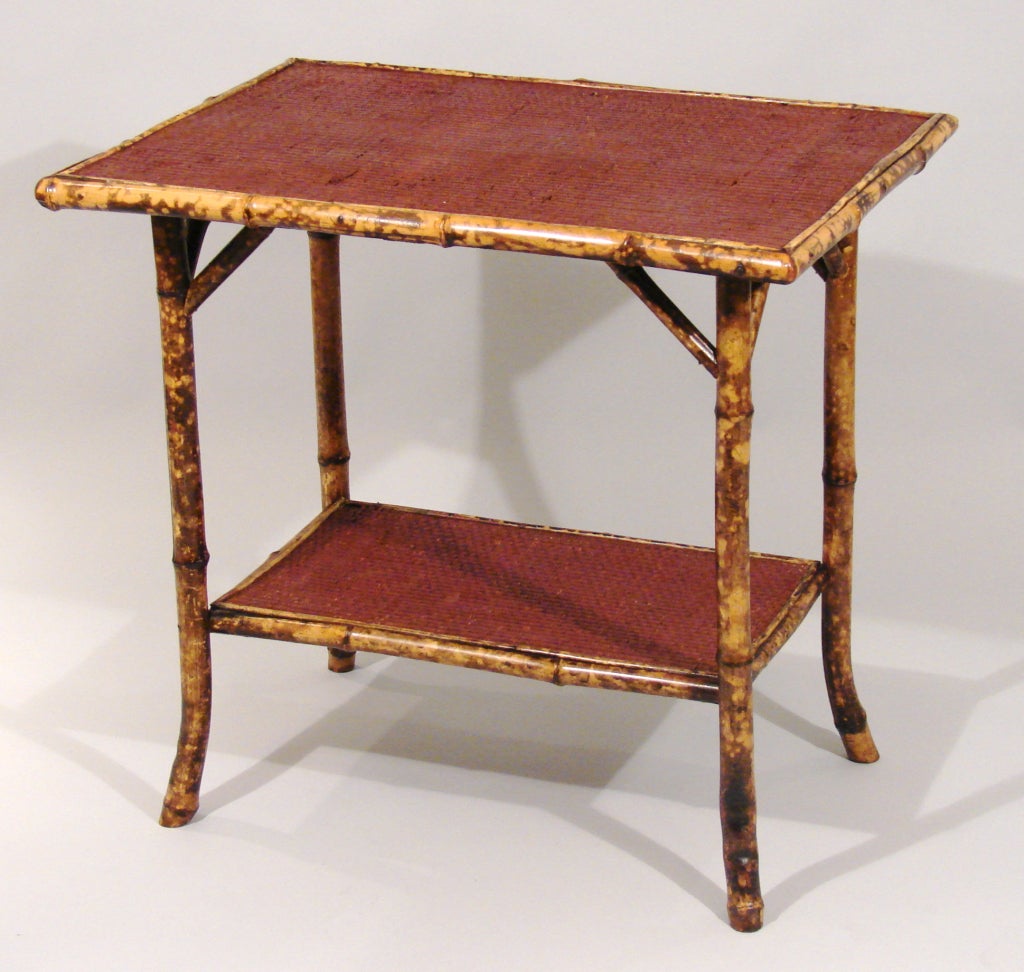 A Victorian bamboo table the overhanging red stained woven top with a shelf below. Probably French, circa 1880.