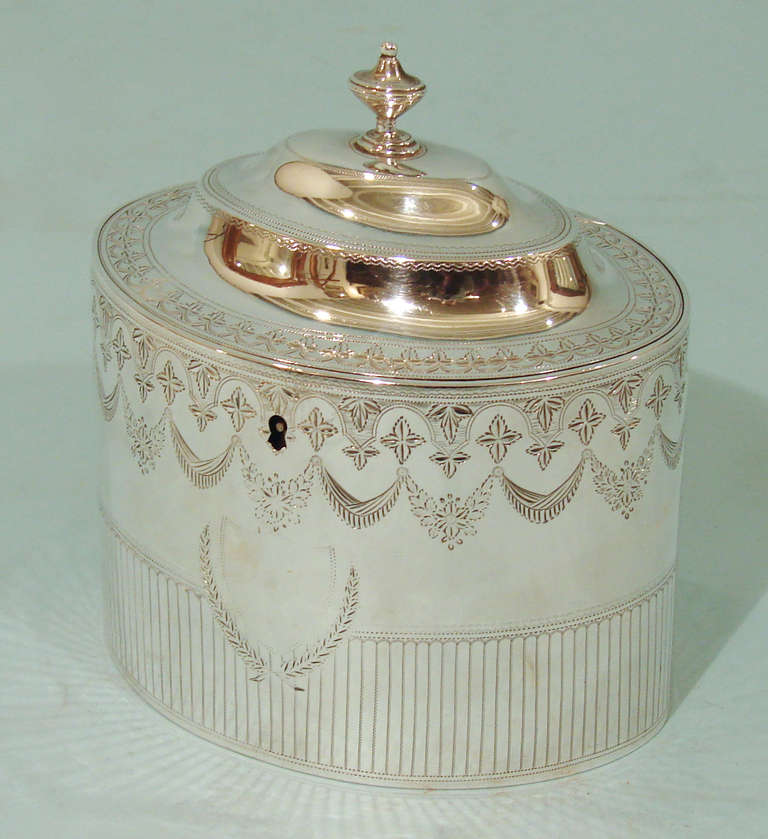 A George III sterling oval lidded tea caddy with bright cut decoration and an armorial in the form of a crane. Hallmarked for London 1796 made by George Smith & Thomas Hayter.