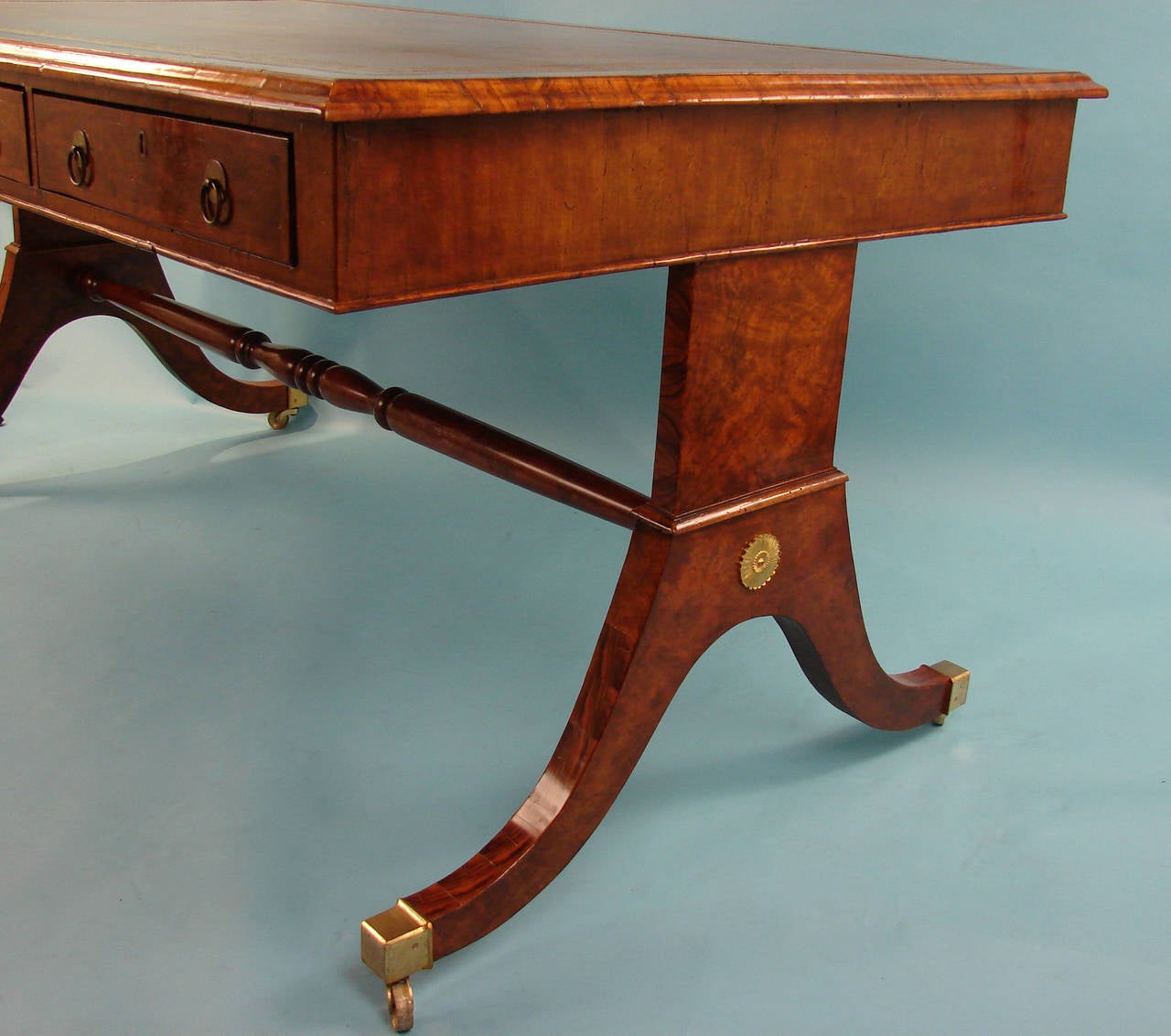 A handsome English burl walnut partners writing table, the gilt-tooled tan leather top above 6 functional frieze drawers, 3 on each side, supported by downswept legs joined by a turned stretcher ending in box casters. Circa 1820.