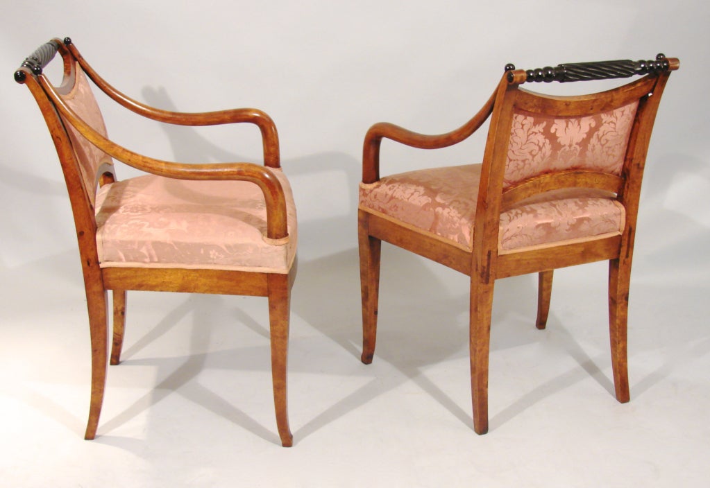 A pretty pair of Neoclassical Northern European maple armchairs, the ebonized rope turned crest rail above downswept arms terminating in square tapered legs. Now upholstered in red damask.