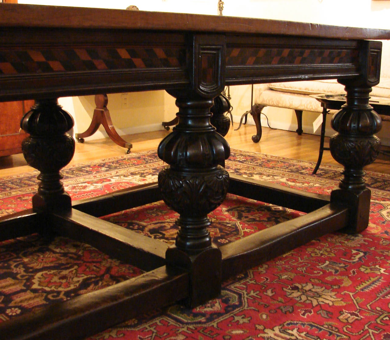 An attractive English Elizabethan style inlaid oak refectory table, the overhanging plank top above a geometrically paint decorated apron supported by 6 substantial carved and turned legs joined by a stretcher, ending on block feet. Circa 1880.