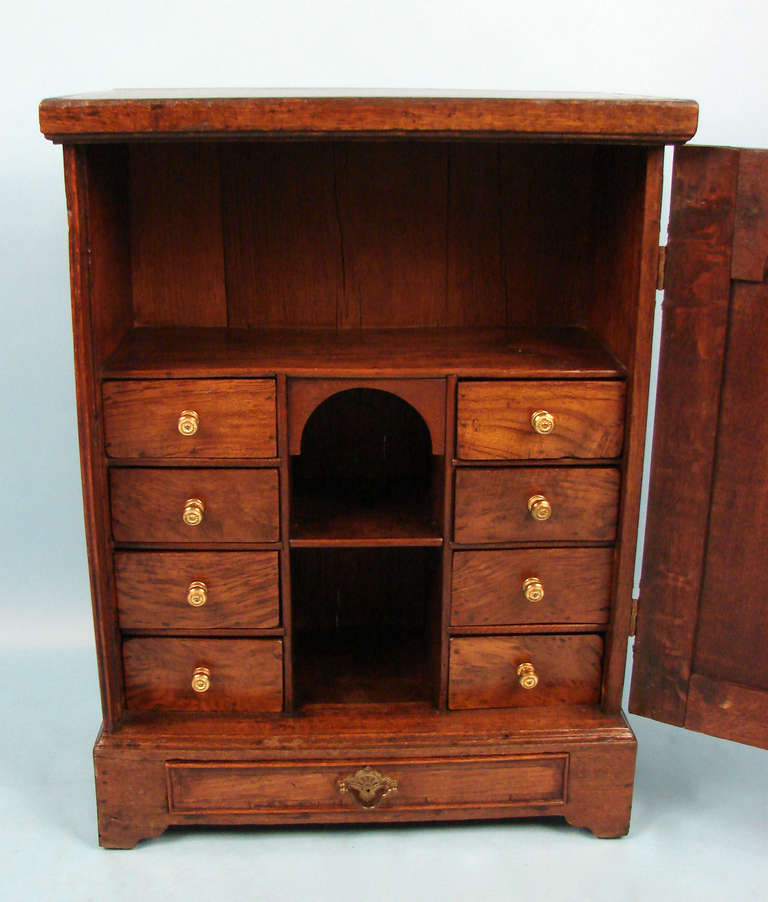 A Georgian oak small cabinet, the satinwood inlaid top and similarly inlaid  paneled door opening to reveal an 8 drawer interior all above a single drawer.