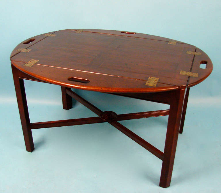 An English Regency period mahogany small scale butler's tray with drop sides,  now mounted on a custom stand of a later date. The stand with molded legs joined by an X stretcher centered with a turned boss.