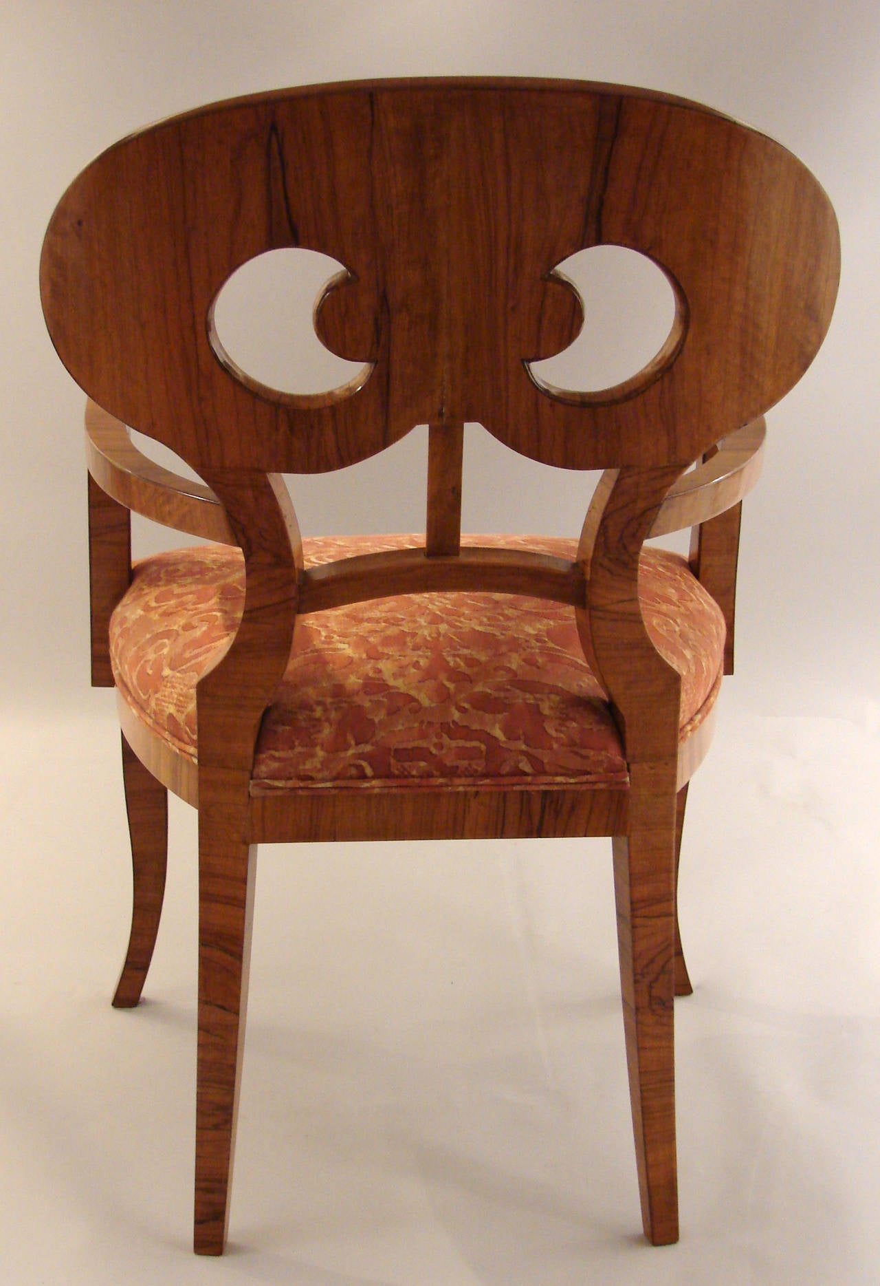 An attractive large-scale Biedermeier style walnut armchair with a pierced oval splat back and shaped square tapering legs, the seat covered in copper colored Fortuny style fabric, circa 1830-1850.