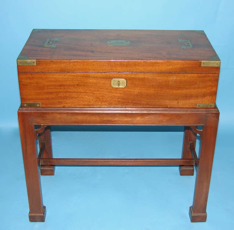 An unusually large fine quality large scale English mahogany brass trimmed and monogrammed campaign-style lap desk with flush-mounted handles on the top and sides, and a fitted replaced leather lined interior, now mounted on a custom stand of a