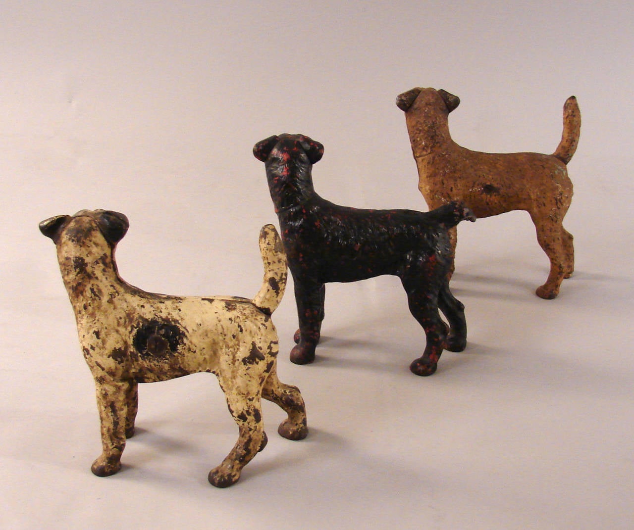 A collection of three Jack Russell terrier dog cast iron door stops retaining their original painted surfaces, possibly by Hubley. circa 1900-1920.