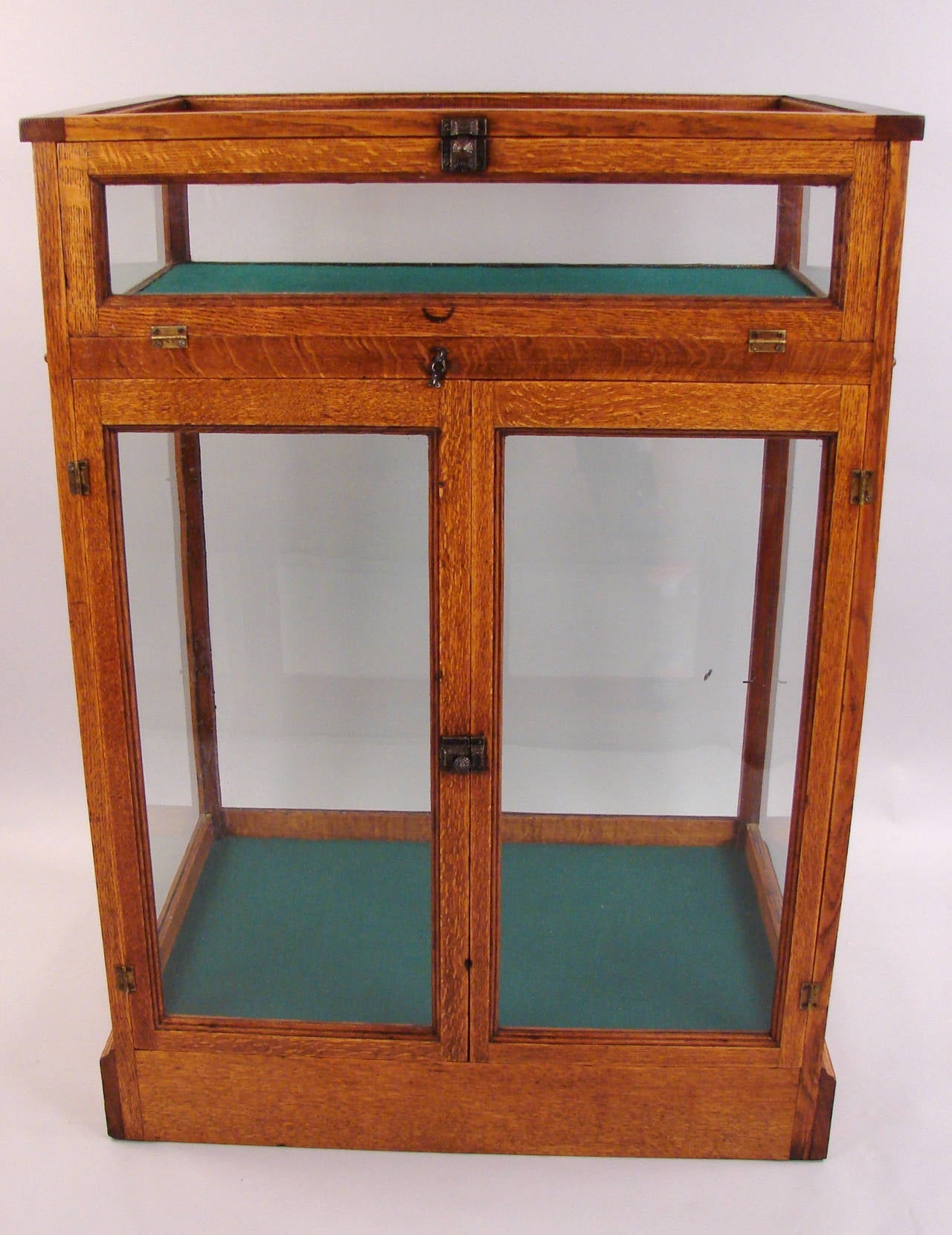 An American oak showcase divided into an upper stage with a removable beveled glass top over a lower stage with 3 later glass shelves. 
Made by and labeled 