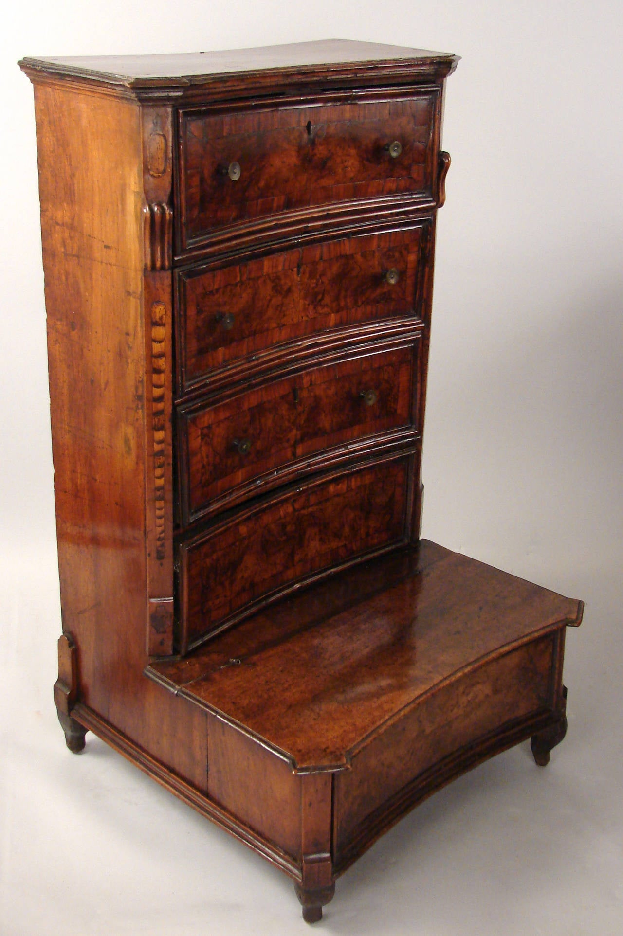 A fine Italian walnut prie-dieu, the shaped case fitted with four crossbanded drawers flanked by inlaid quarter columns above a hinged cabinet door resting on turned feet, late 17th century.