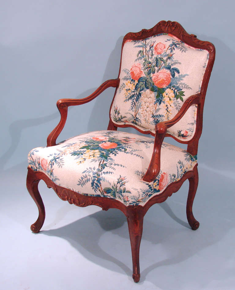 A Louis XV style oak armchair of typical form, the apron with a central shell decoration resting on cabriole legs with scroll feet. Upholstered in a floral polished cotton fabric in very good condition.