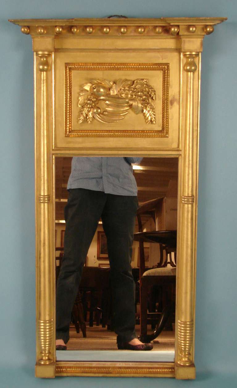 An American Federal period giltwood and gesso wall mirror, the upper portion with a cornucopia of fruit. Retains its original gilding and mirror plate. Provenance: Marguerite Riordan, Stonington Ct.
