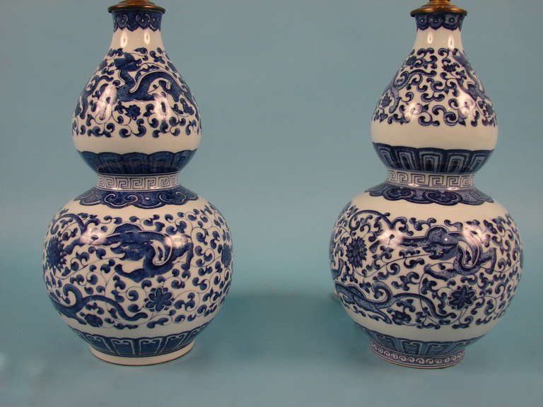 A pretty pair of Chinese blue and white vase  of bottleneck form with overall foliate decoration with mythological creatures now as lamps.