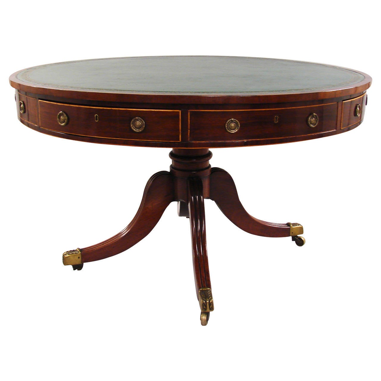 A good quality English Regency period mahogany drum table, the inset green gilt tooled leather top above four functional and four false inlaid frieze drawers, supported on a reeded quadripartite base ending in brass casters.