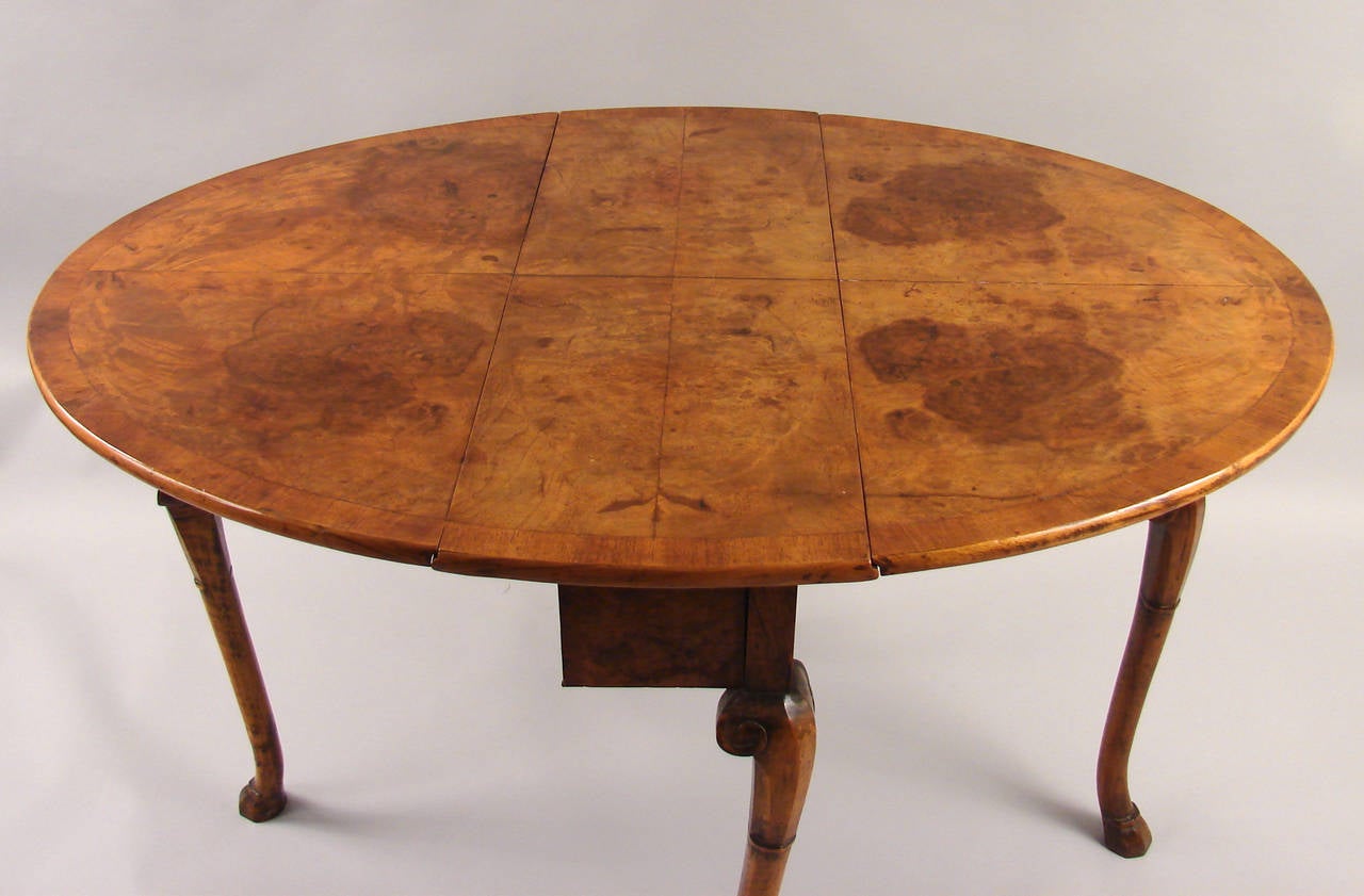 A Northern European burl walnut drop-leaf table in the English taste, the well-figured quarter veneered top with conforming crossbanding above cabriole legs ending in simple hoof feet, circa 1800-1840.