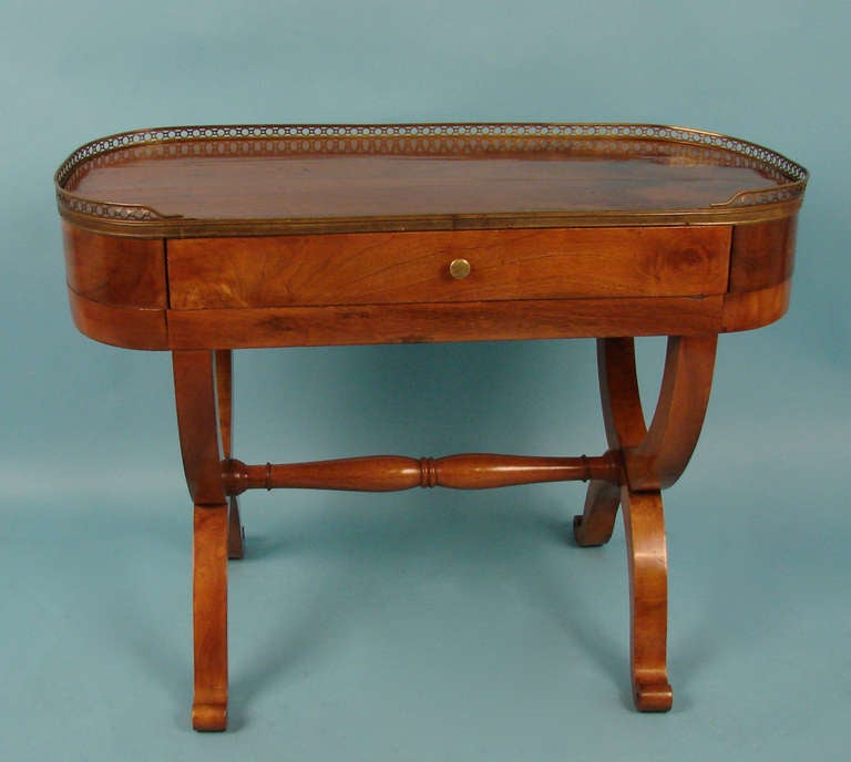 A very pretty French Charles X period walnut oval side table with brass gallery, the figured top above a single drawer supported by a curule form base joined by a turned stretcher. Circa 1825.